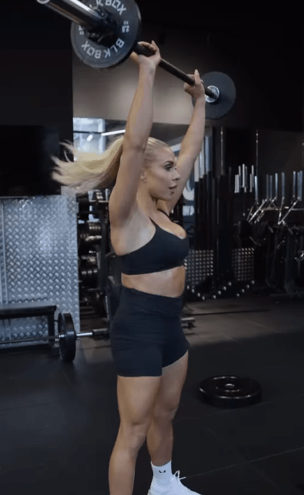 Woman performing overhead barbell press.