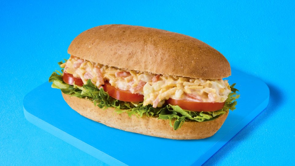 Sandwich with egg salad and tomato on a whole wheat roll.