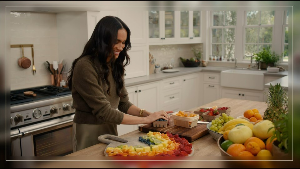 Meghan Markle arranging fruit in a kitchen.