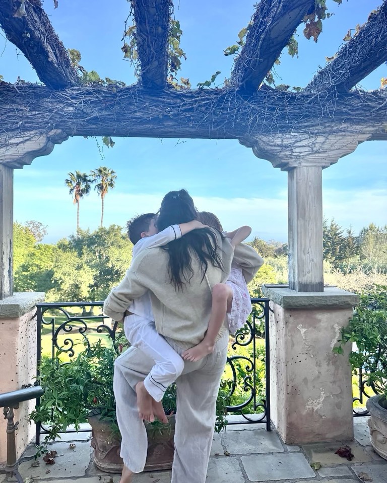 Woman holding two children on a balcony.