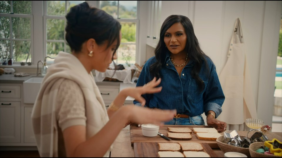 Meghan Markle and Mindy Kaling making sandwiches in a kitchen.