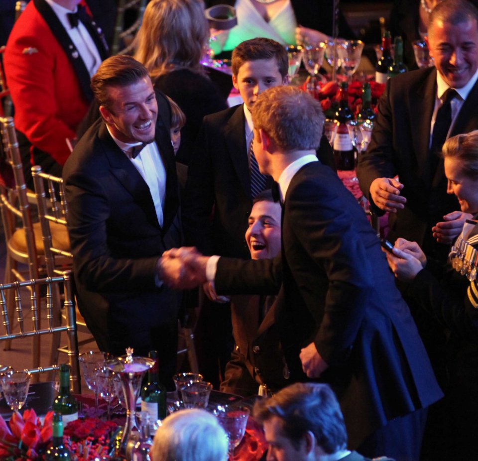 Prince Harry and David Beckham shaking hands at an awards ceremony.