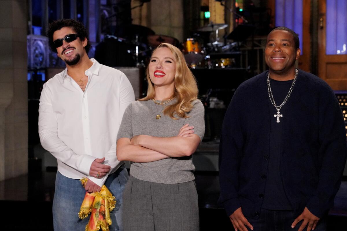 Three people stand beside each other on a stage 