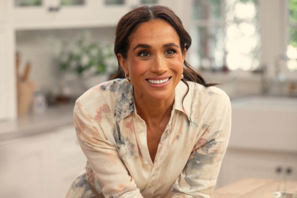 Meghan Markle smiling in a kitchen.
