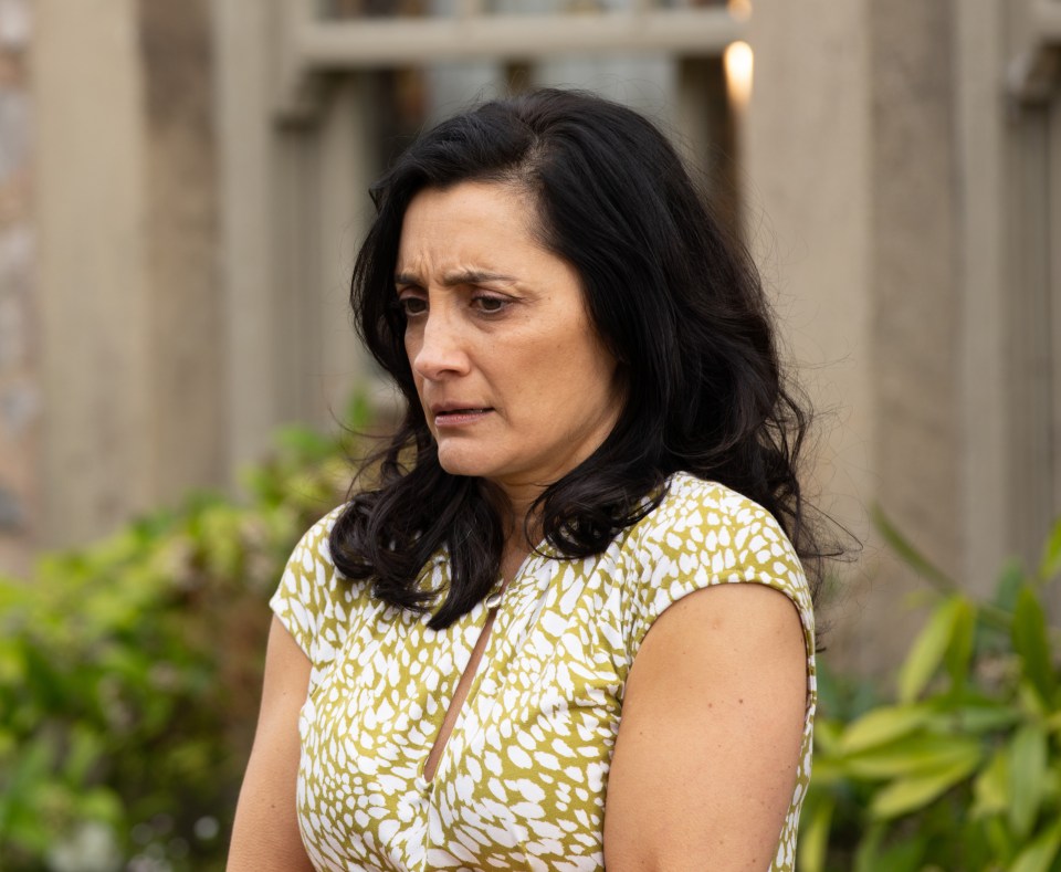 A woman with dark hair looks down.
