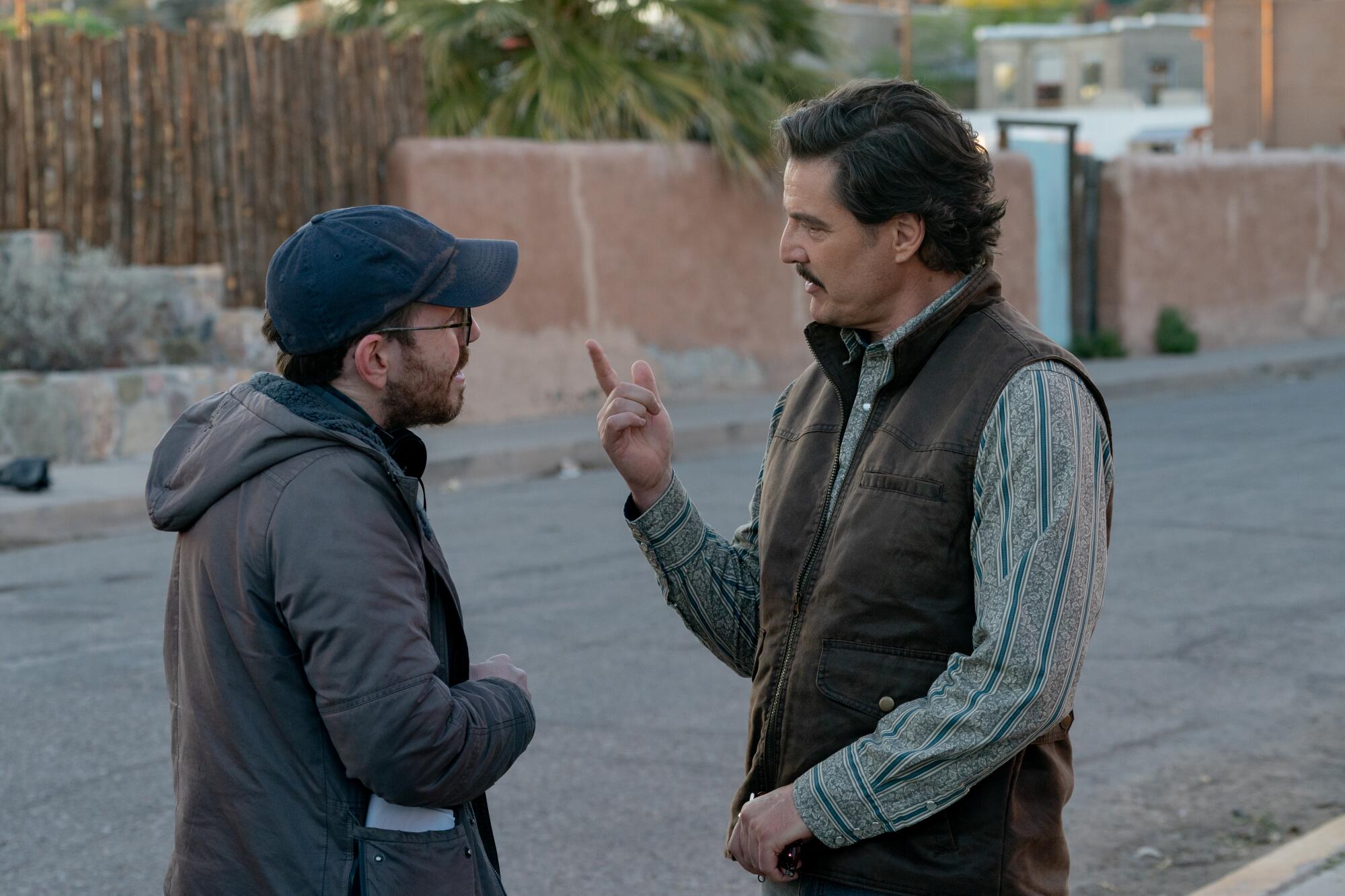 A director speaks with an actor on a street set.