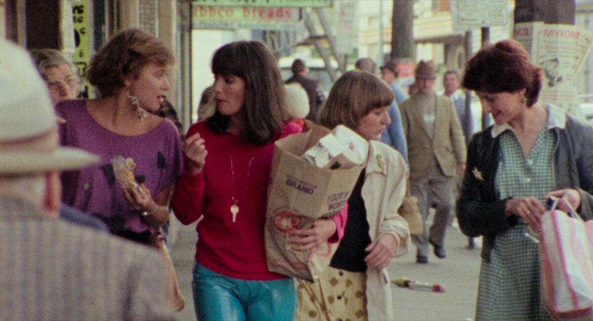 A woman holding a shopping bag has a conversation on the sidewalk.