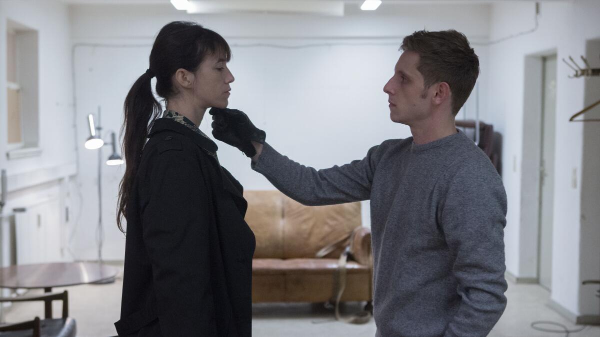 A woman's chin is touched by a man wearing black gloves.