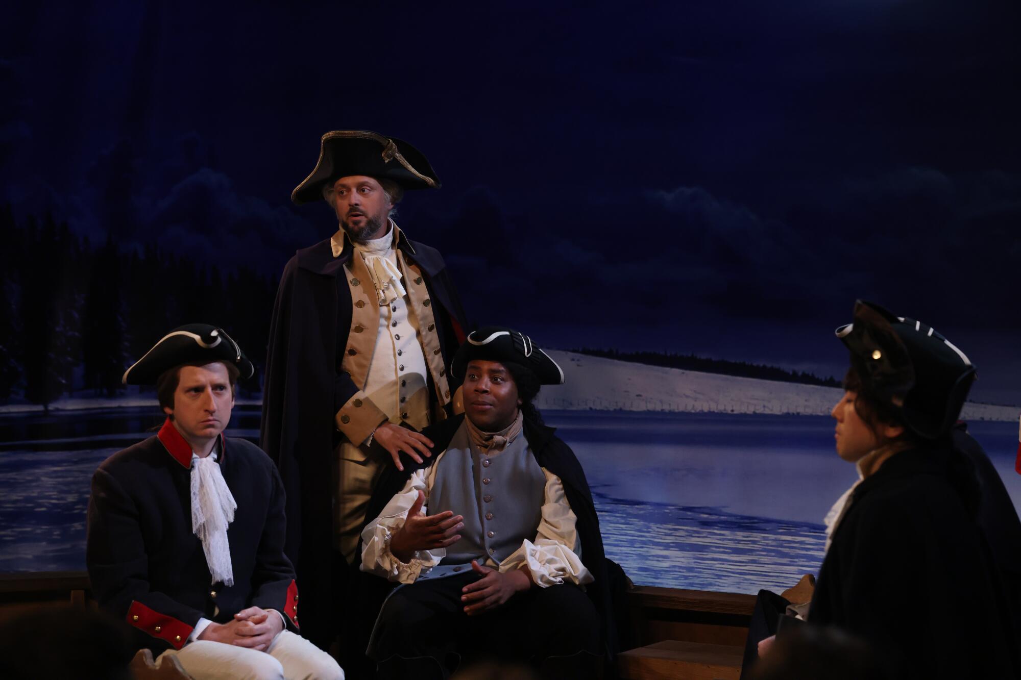 Four men sitting in a boat wearing 18th century tricorne hats and blue and white military uniforms.