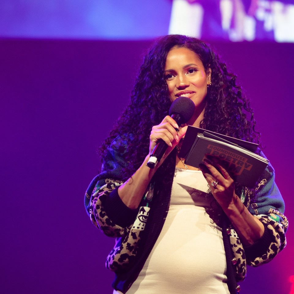 Vick Hope speaking at an event, holding a microphone and a book.