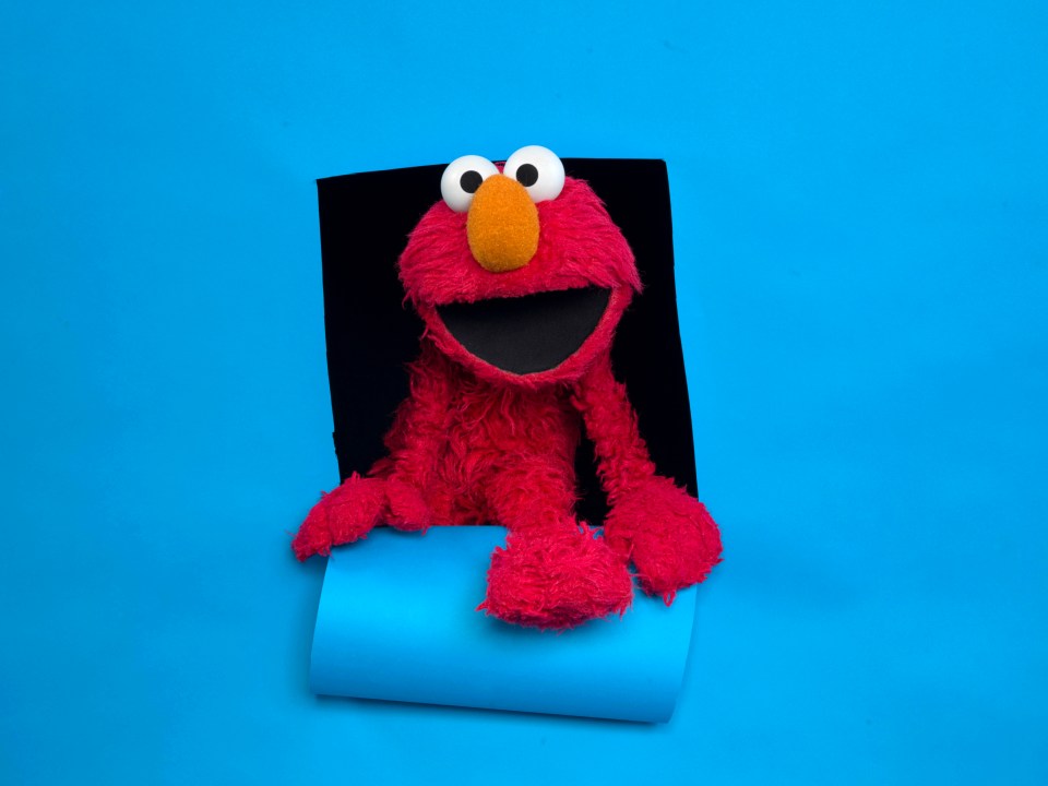 Elmo peeking through a hole in a blue background.