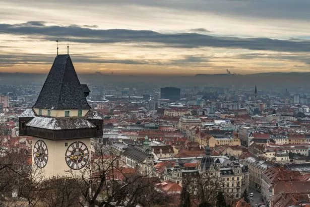 the famous Graz clock tower on a December day. In the background the city of Graz is visible