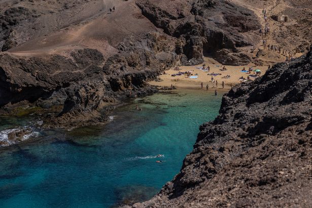 People sunbathe and swim at the Playa de Papagayo, Lanzarote