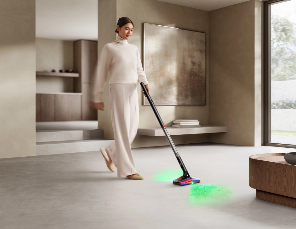 Woman using a stick vacuum cleaner.