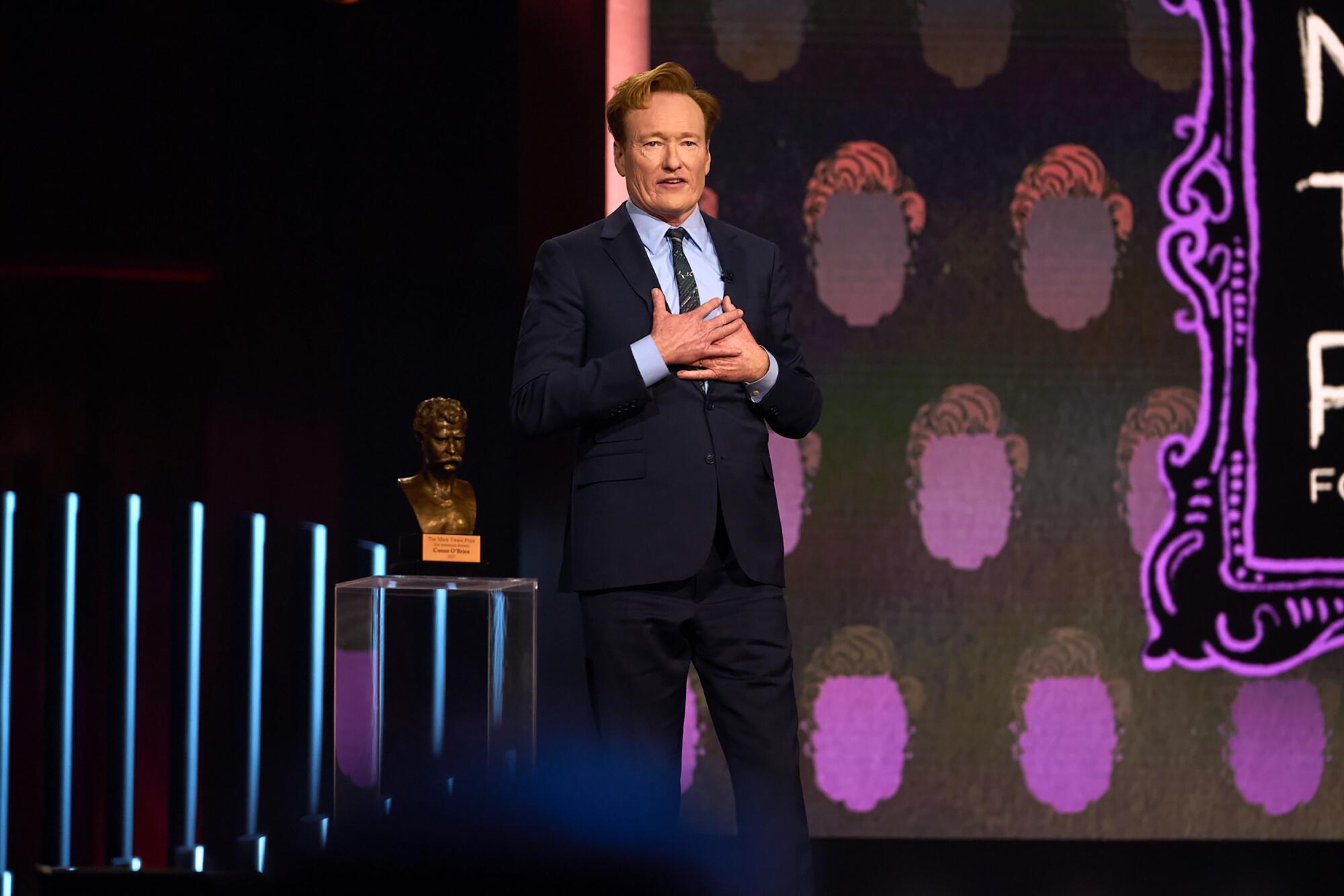 A man in a suit stands on a stage