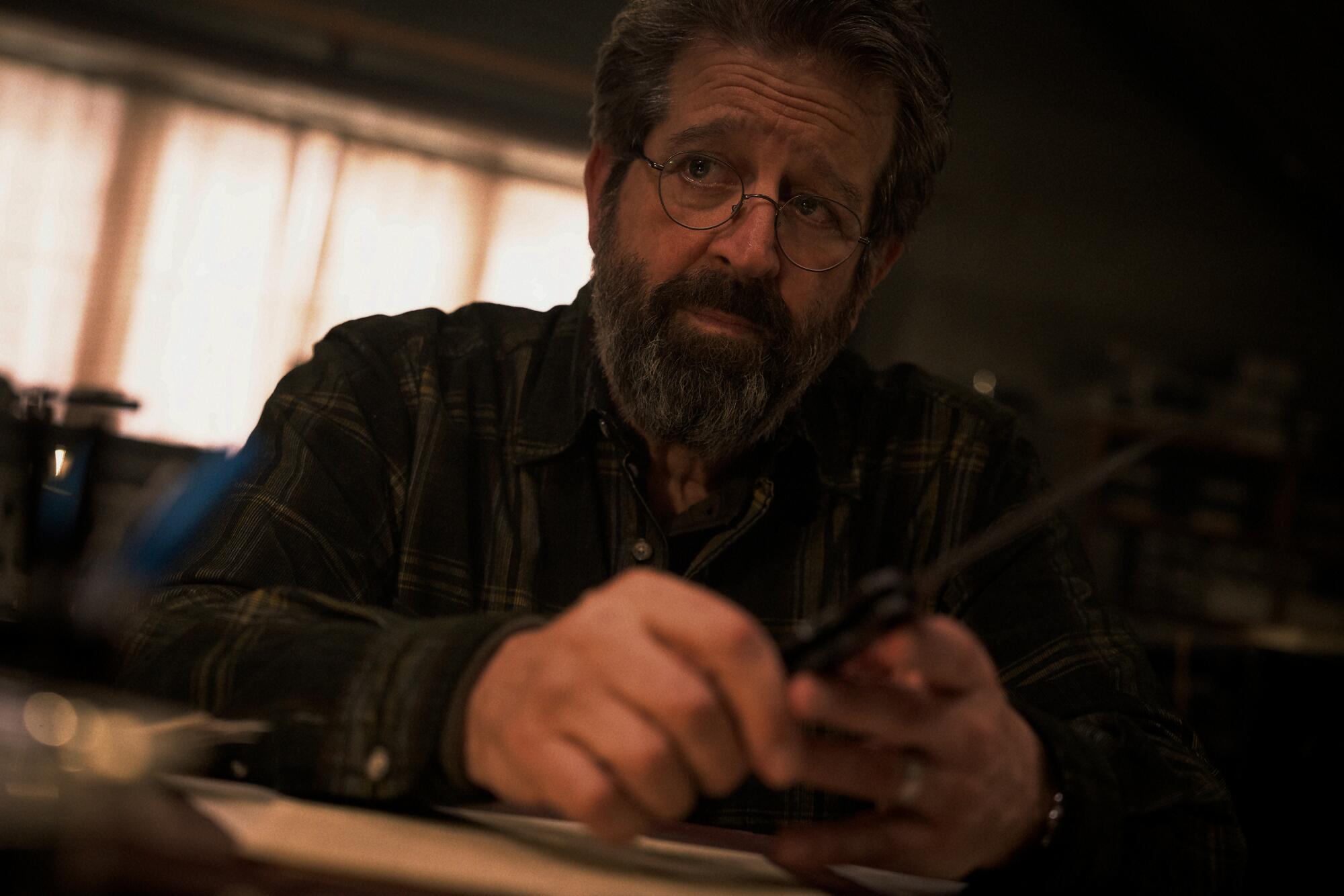 A bearded man plays with a knife.