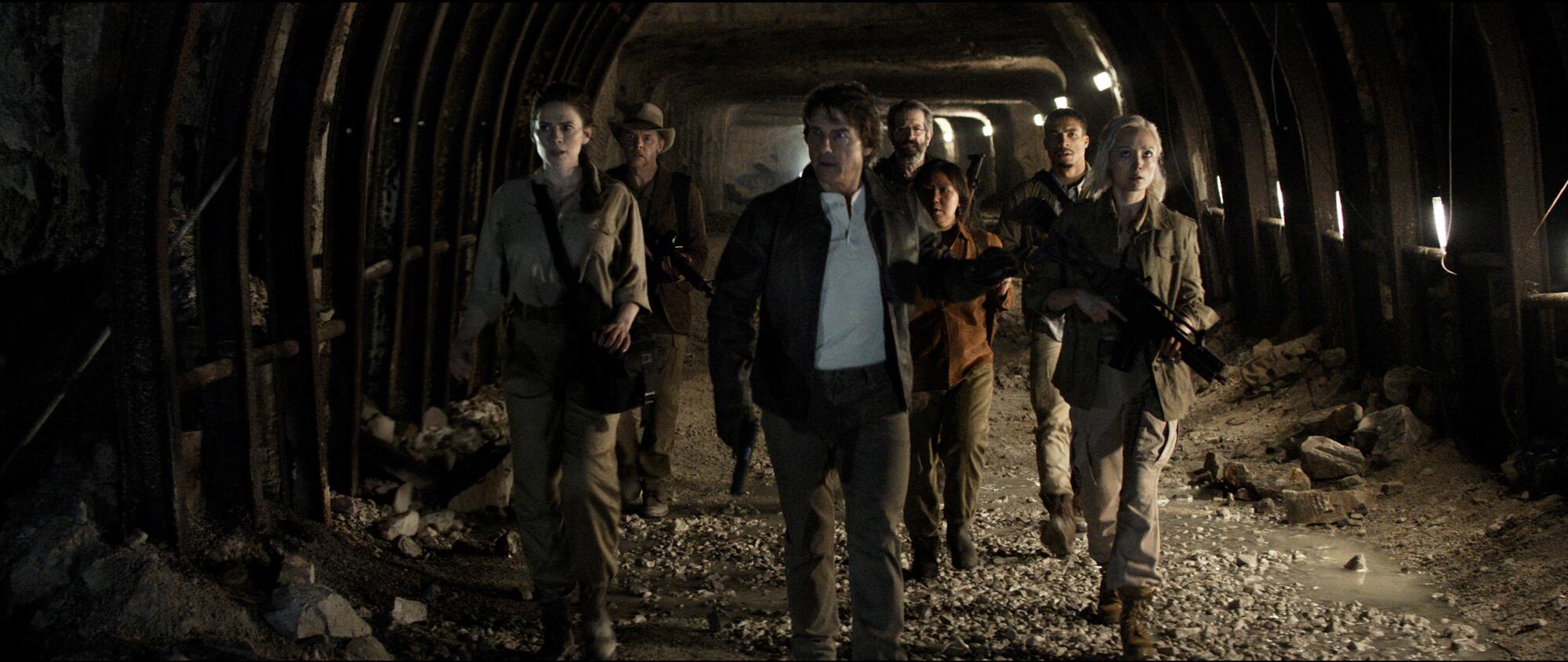 Several team members walk through a cave.