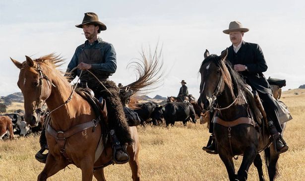 Two cowboys ride on horses