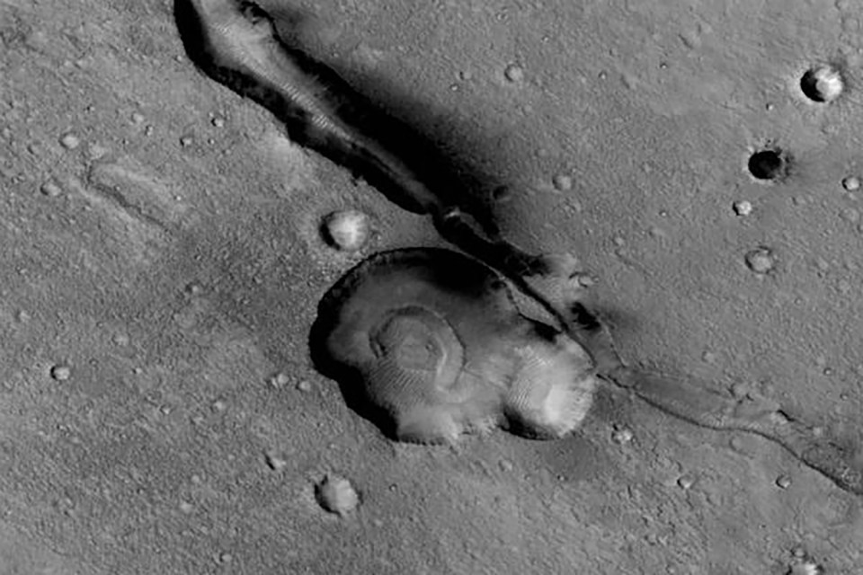 Martian surface with a crater and a long, narrow channel.