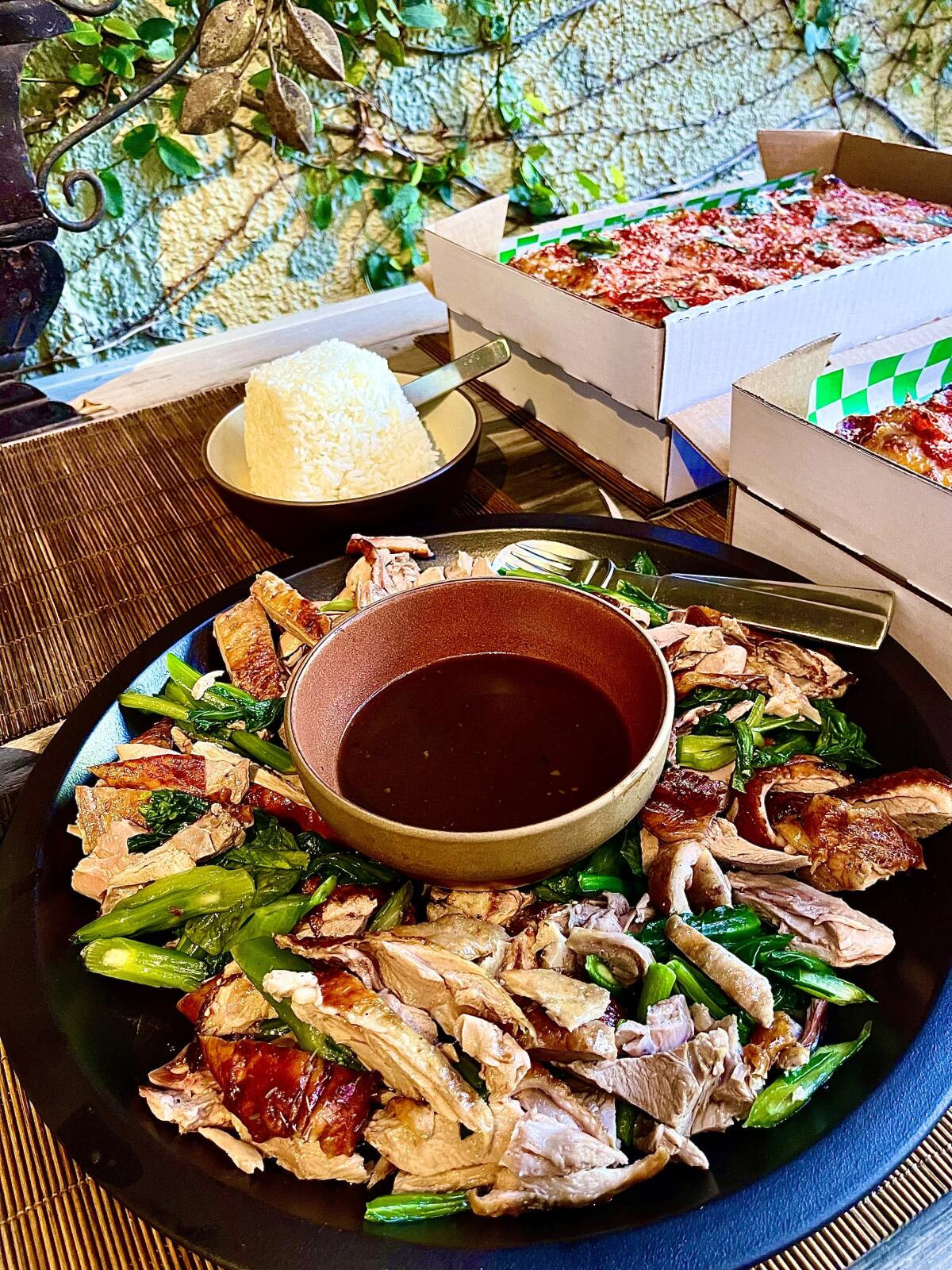 A platter from Thai Town's Roasted Duck by Pa Ord with boxes of pizza from Quarter Sheets in the background.