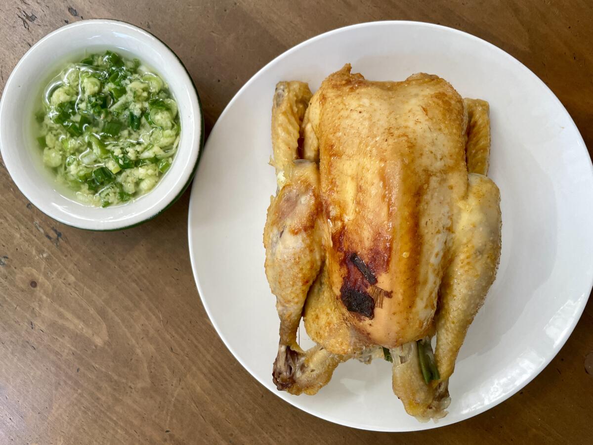 A whole chicken is cooked in the rice cooker and served alongside a condiment made with ginger and scallions.
