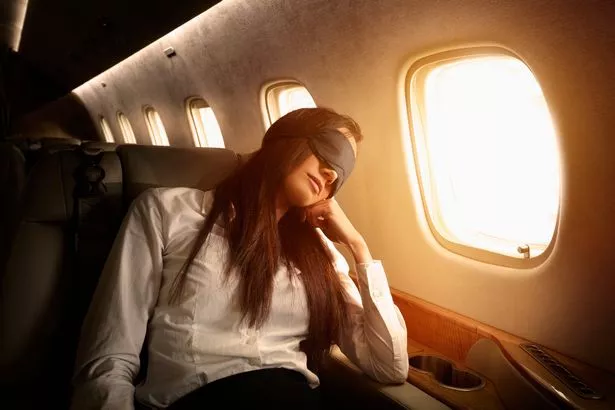 Woman asleep and wearing an eye mask on board a flight