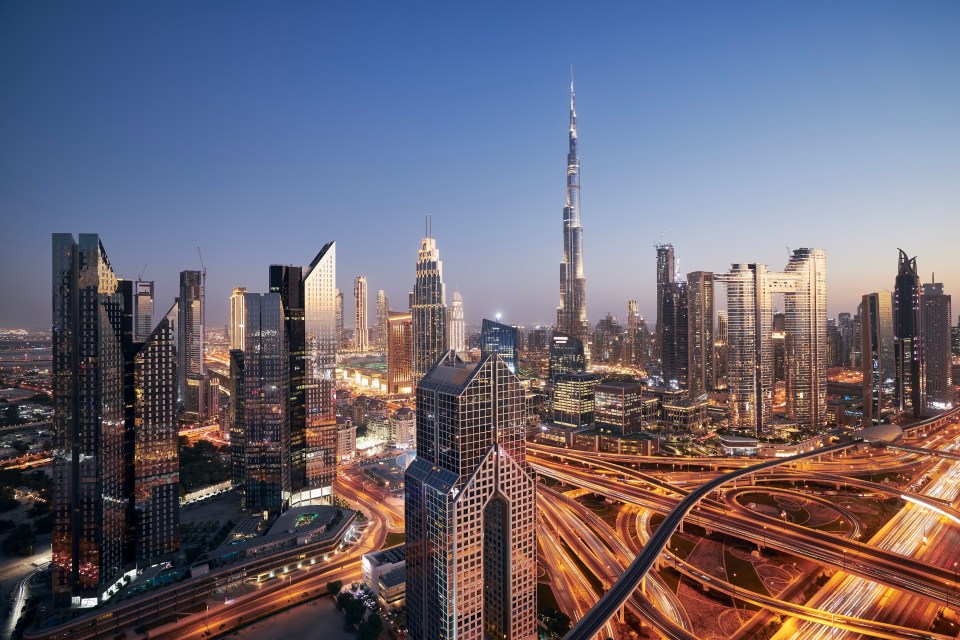 Nighttime view of Dubai's illuminated skyline, including the Burj Khalifa.