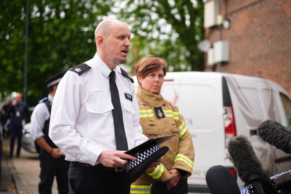 Police and fire officials speaking to the media at a crime scene.