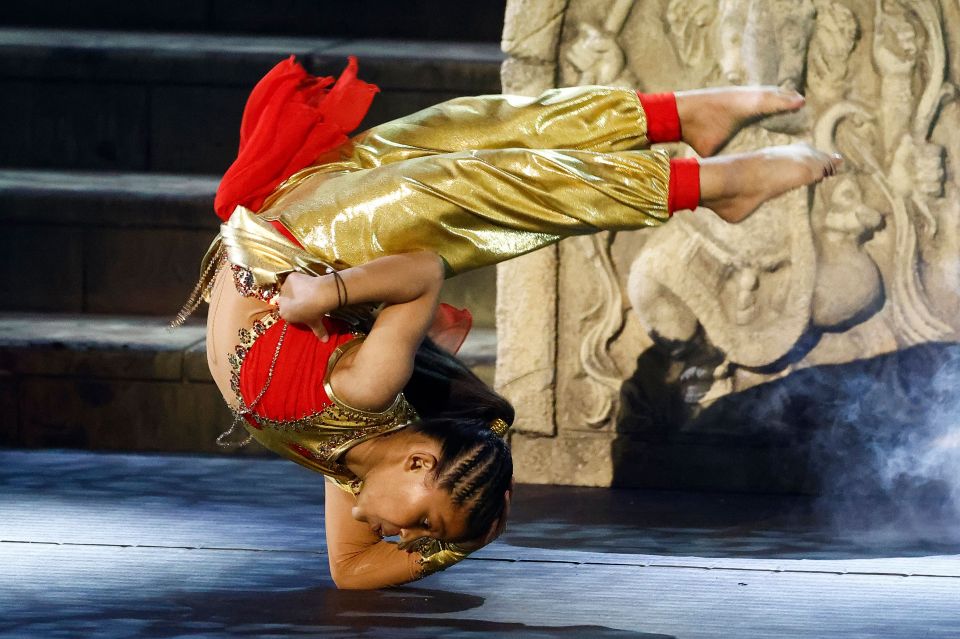 A young girl in a gold and red costume performing a handstand on Britain's Got Talent.