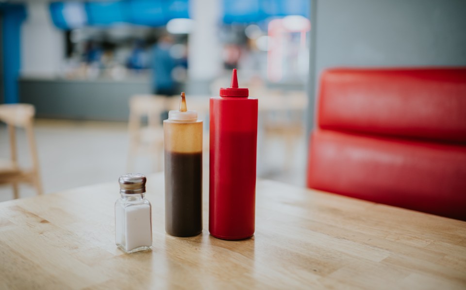 Condiment bottles and salt shaker on a restaurant table.