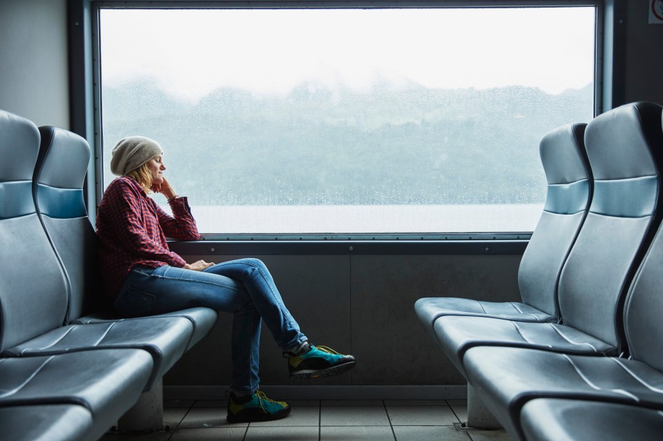 Woman sleeping on a ferry, looking out the window.