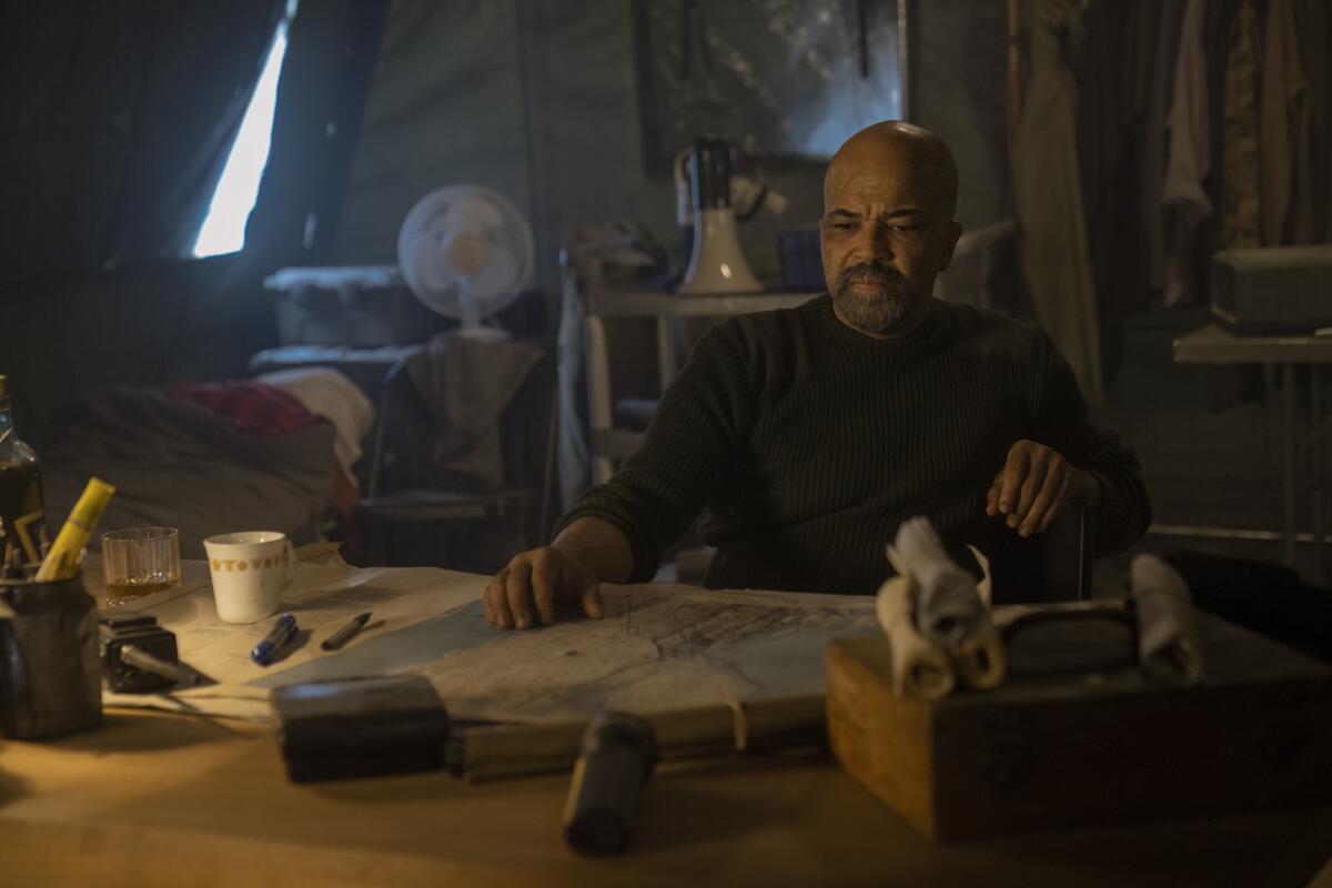 Jeffrey Wright sitting at a desk with a map on it