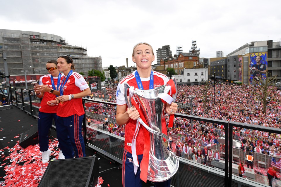 Chloe Kelly of Arsenal holding the UEFA Women's Champions League trophy, celebrating with teammates and fans.