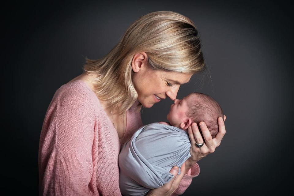 Woman holding and nuzzling her newborn baby.