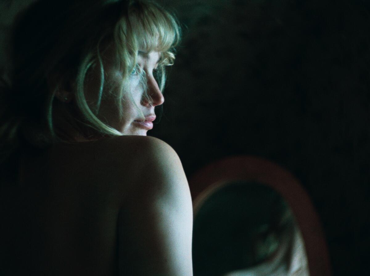 A woman looks over her shoulder, away from a mirror.