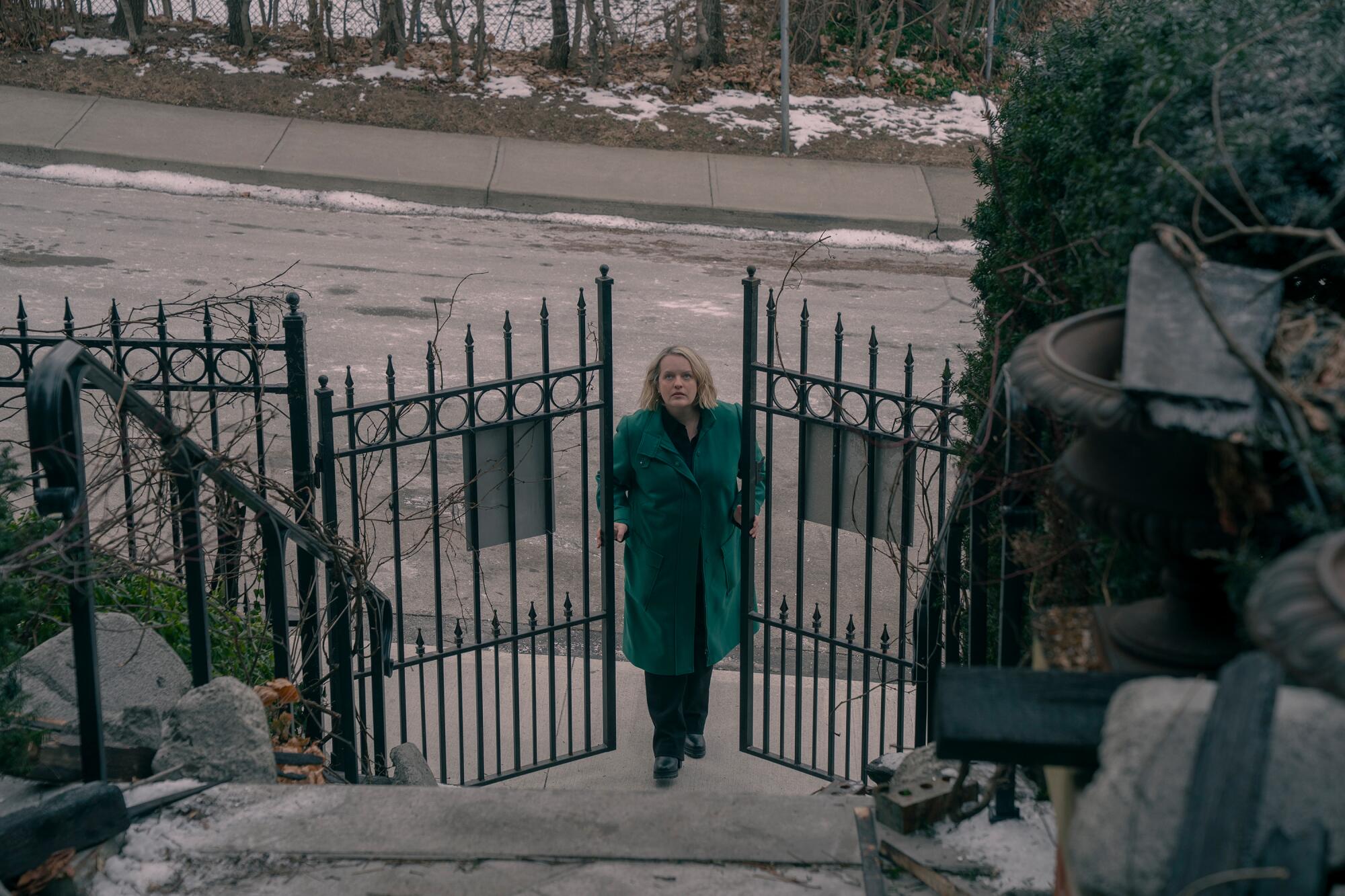 A woman in a blue coat approaches a gate
