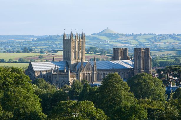 View of Wells Cathedral across the Somerset Levels towards Glastonbury Tor in the distance