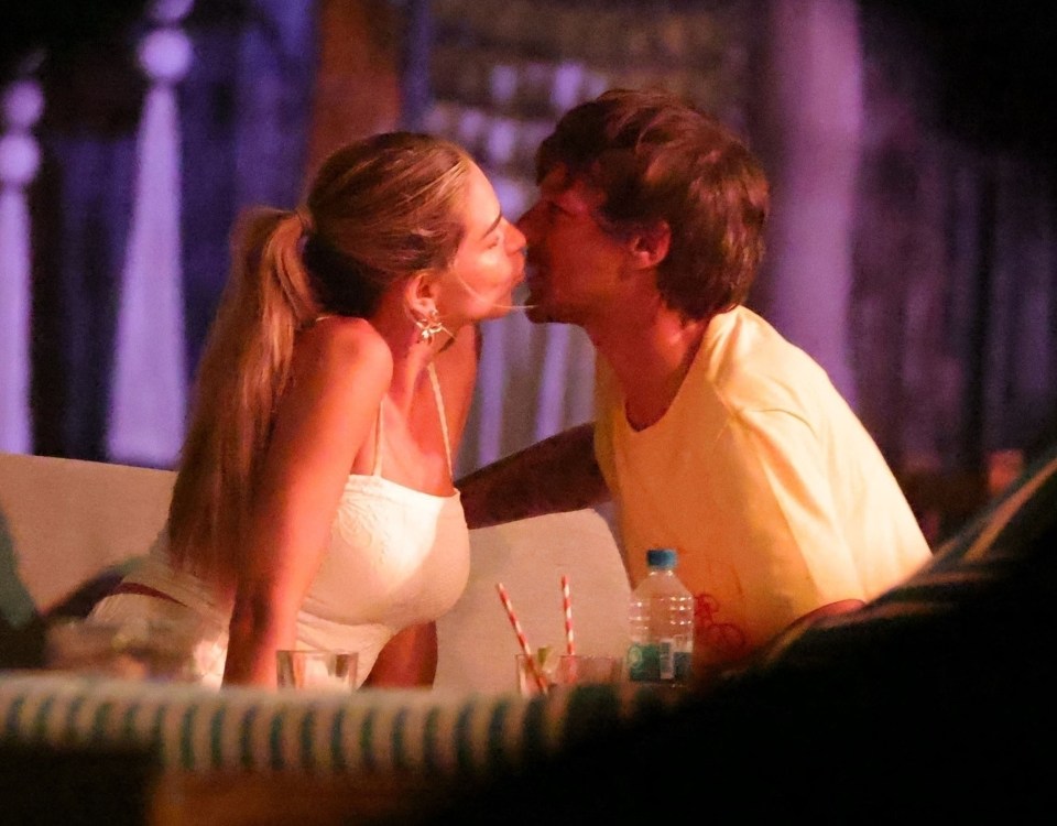 Louis Tomlinson and Zara McDermott kissing at a table.