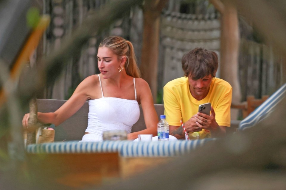 Louis Tomlinson and Zara McDermott sitting together at a table outdoors.