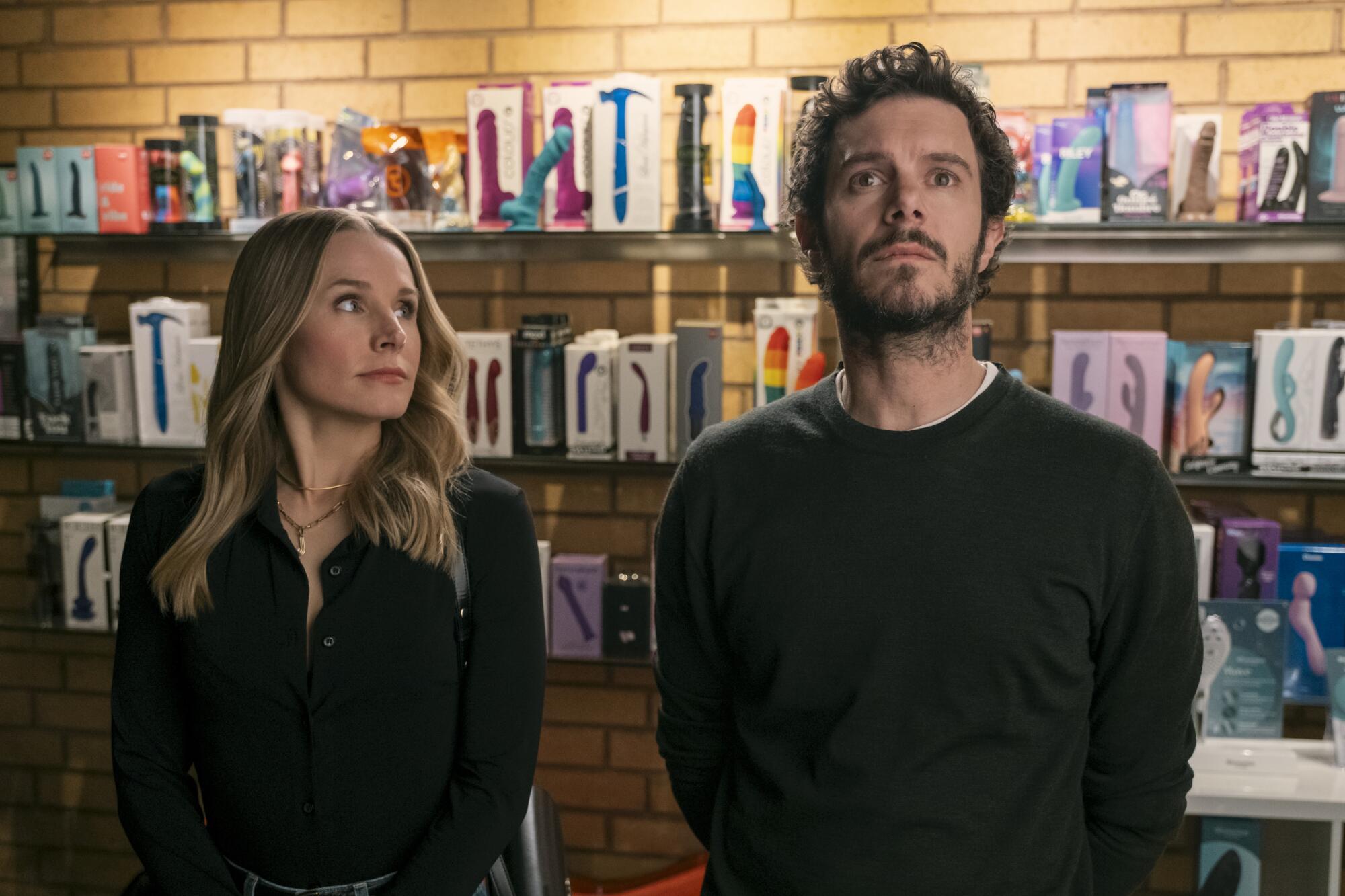 A woman and a man stand in a store in front of a display of vibrators.