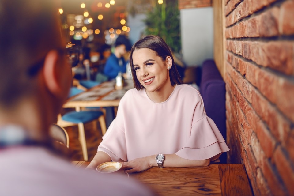 Young woman smiling at man in cafe.