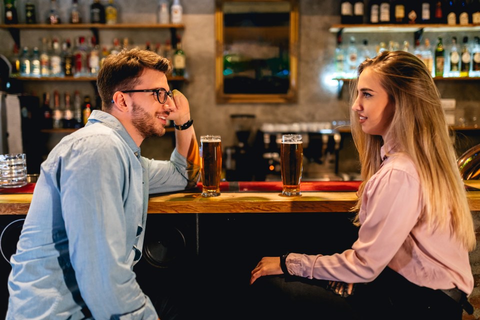 Young couple on a first date at a pub, drinking beer and talking.