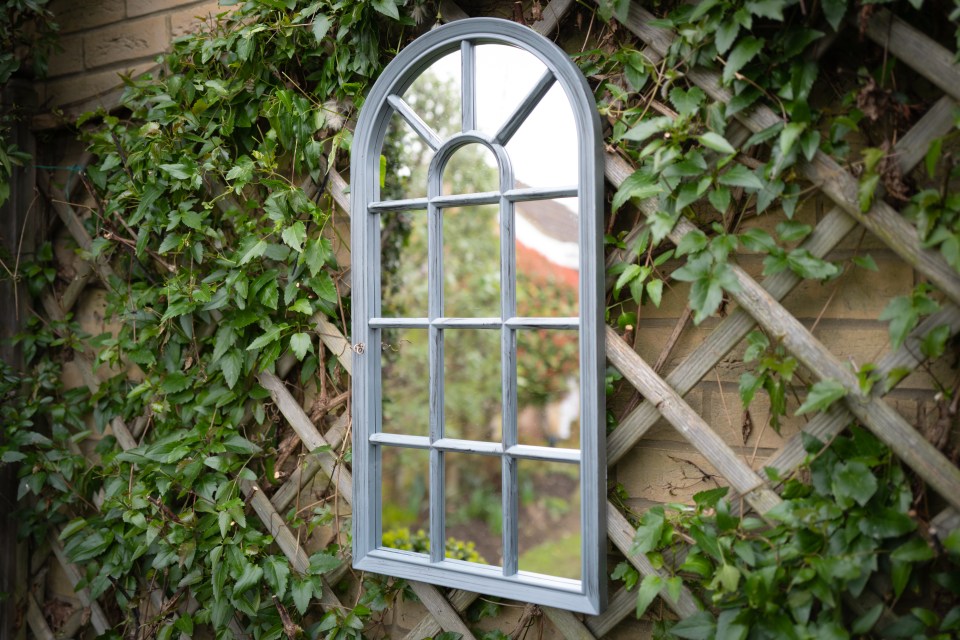 Ornate mirror on a garden trellis.