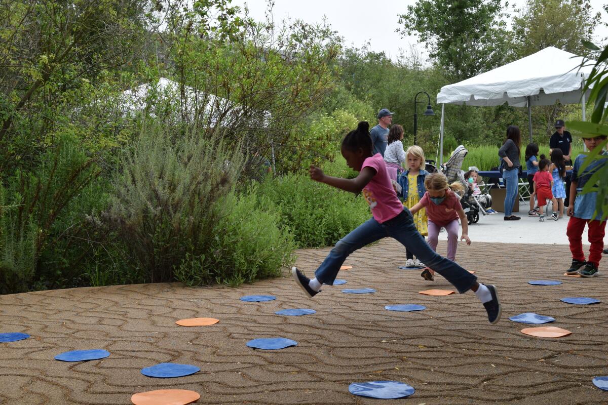 Child jumping in the play area of a park.