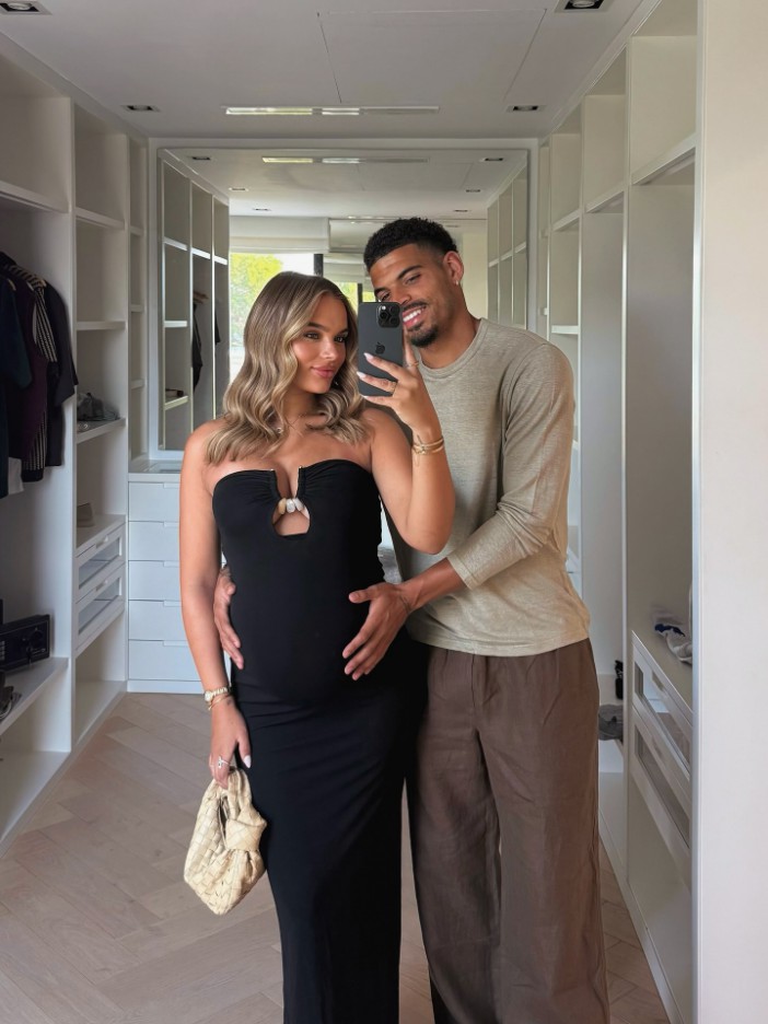 Pregnant woman and man taking a selfie in a walk-in closet.