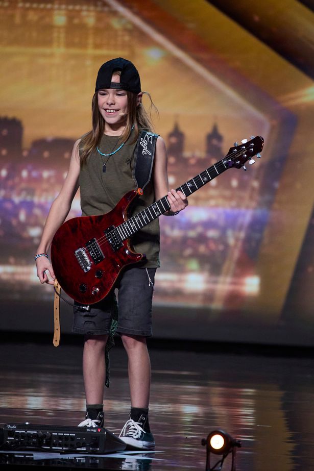 Olly Pearson holding a guitar on the BGT stage in an audition.