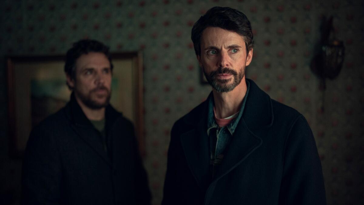 Two men stand in a room