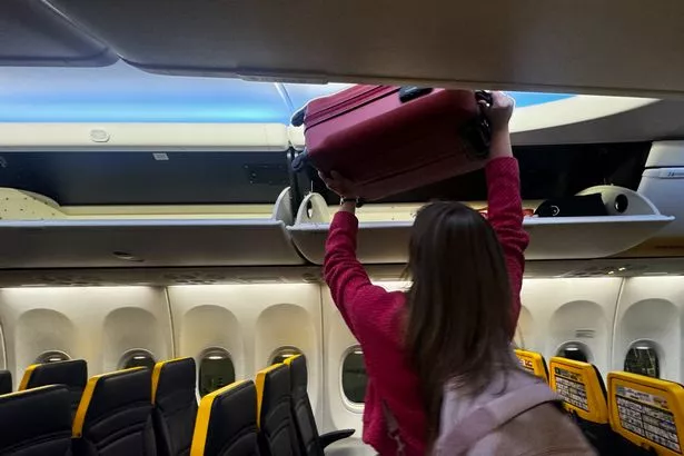 A person stacks luggages in an overhead bin at plane at the airport in Treviso, Italy on May 19, 2025. (Photo by Jakub Porzycki/NurPhoto via Getty Images)