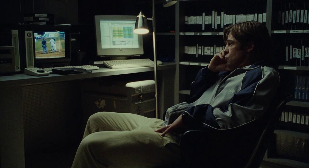 A man sits glumly in an office, thinking.