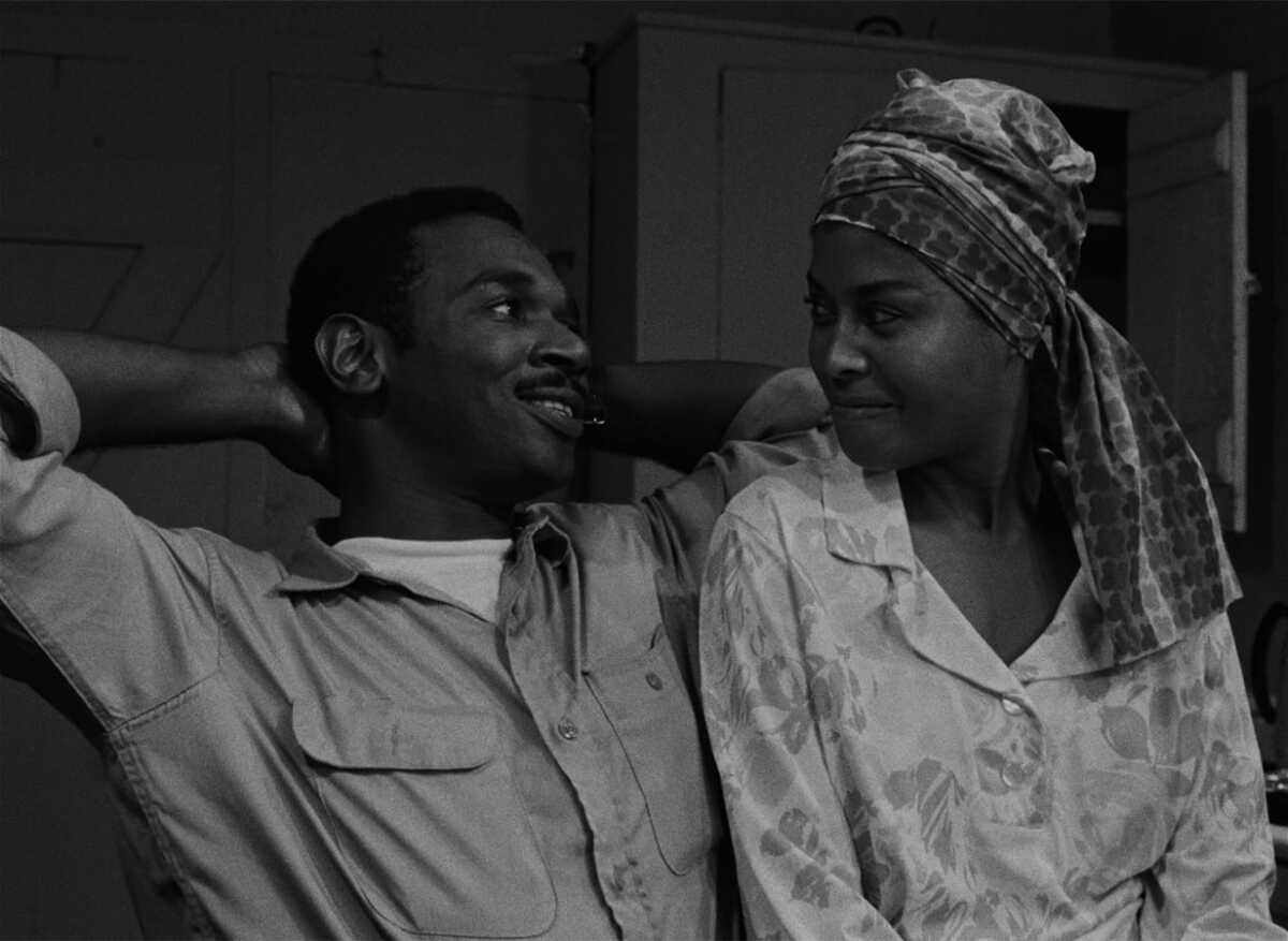 A man smiles at a woman sitting next to him.